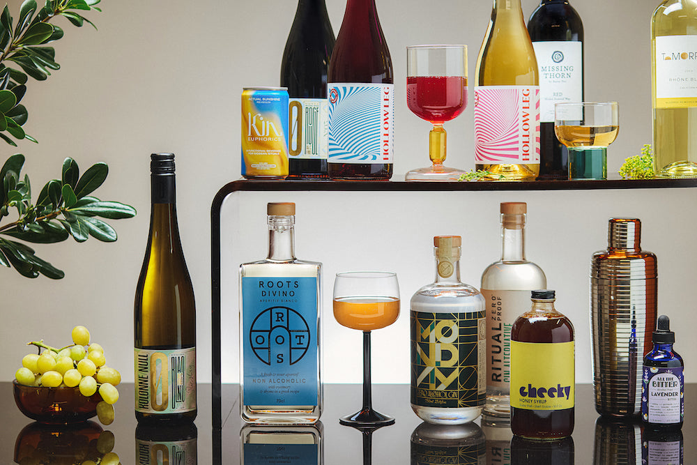 Collection of various bottles and glasses with drinks on a reflective surface.