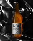 Bottle of 'NON' beer with a label on a black and white textured background
