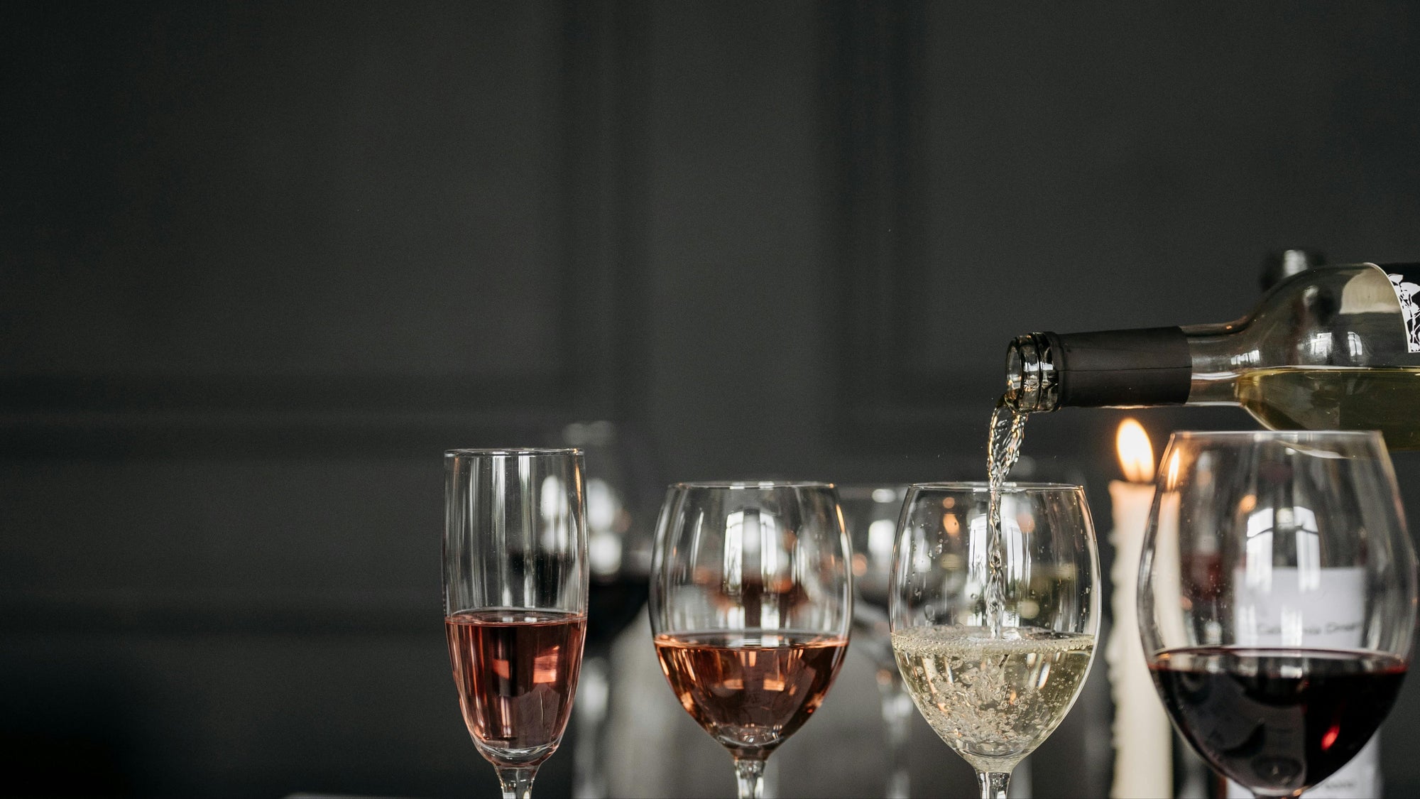 Pouring non-alcoholic white wine into a glass alongside rosé and red wine varieties