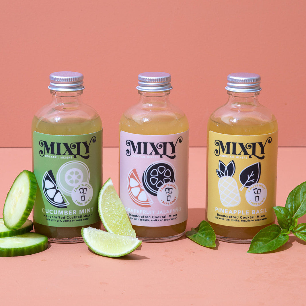 Three bottles of Mixly drinks with labels on a pink background