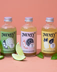 Three bottles of Mixly drinks with labels on a pink background