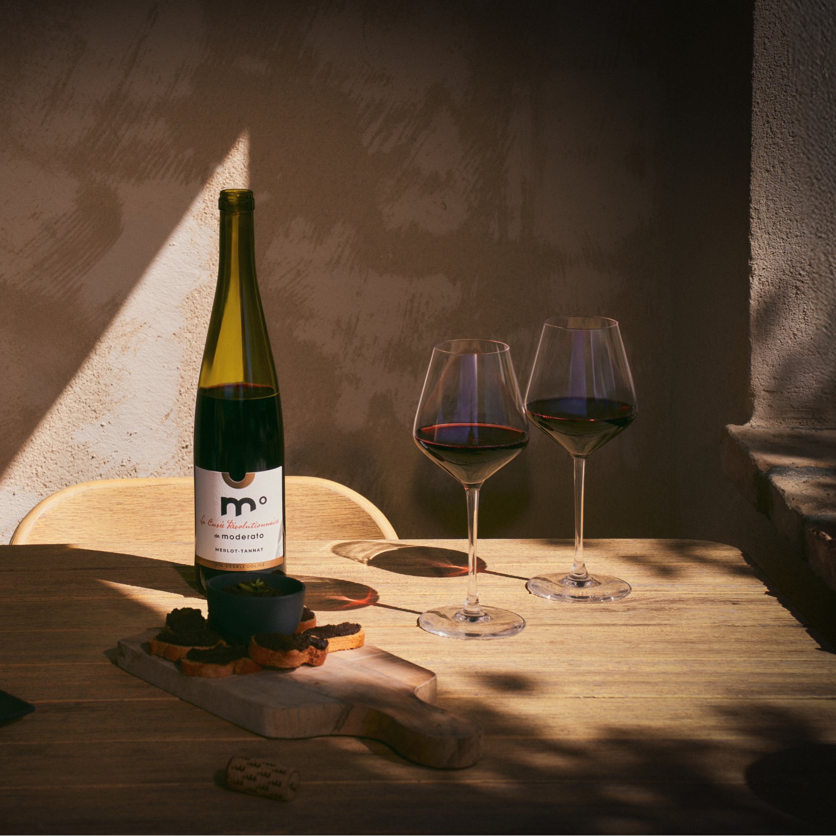 Wine bottle and glasses on a wooden table with warm lighting