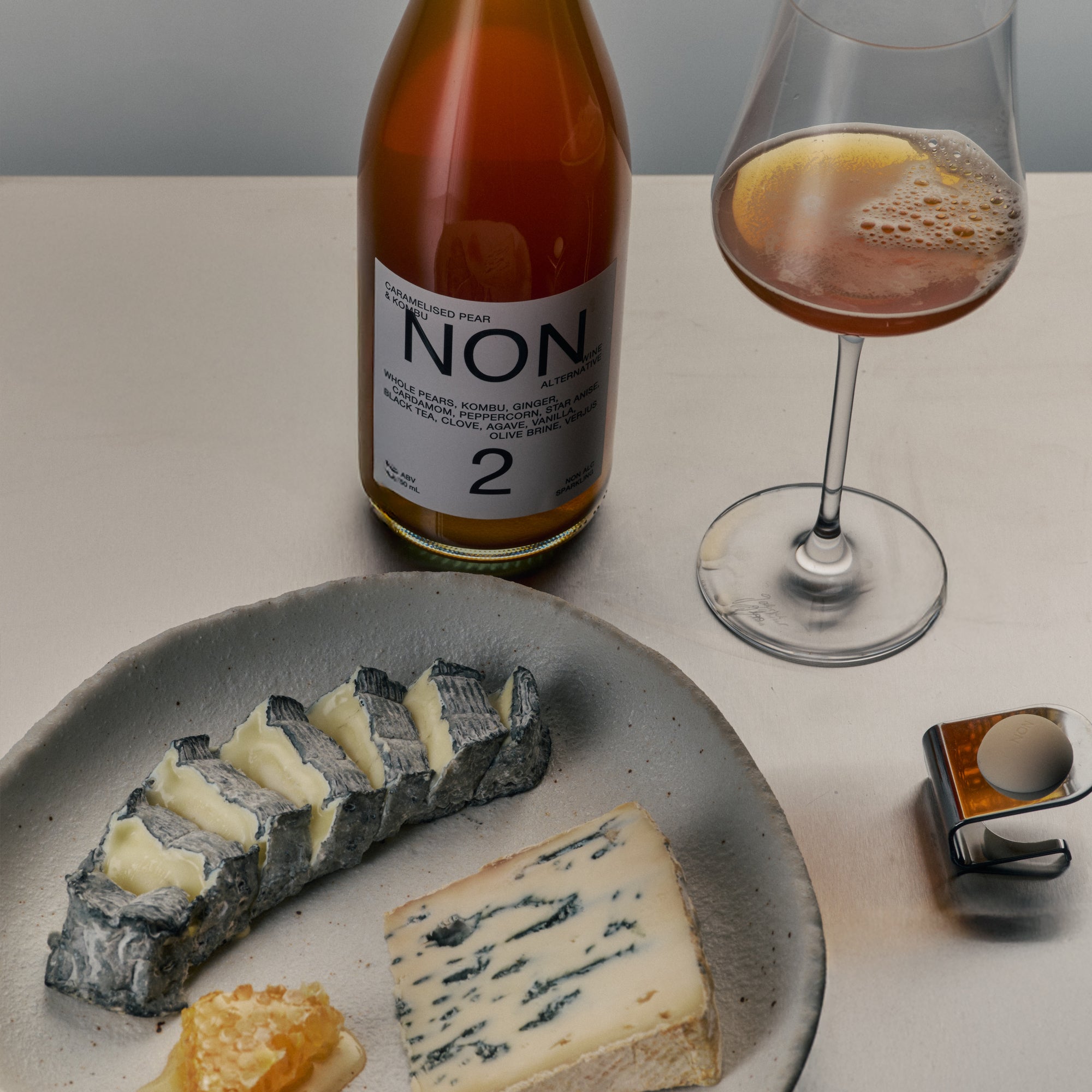 Bottle of Non alcoholic wine, glass with drink, and plate of cheese on a table