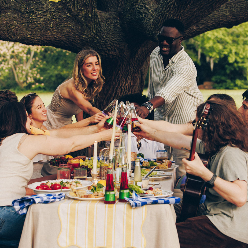 Group of people enjoying a meal outdoors under a tree
