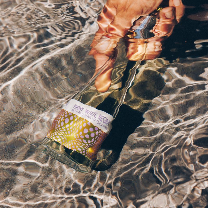 Hand holding a bottle labeled &#39;Macky White Vegas&#39; underwater with clear water.