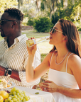 Man and woman enjoying a picnic in a park with food and drinks.