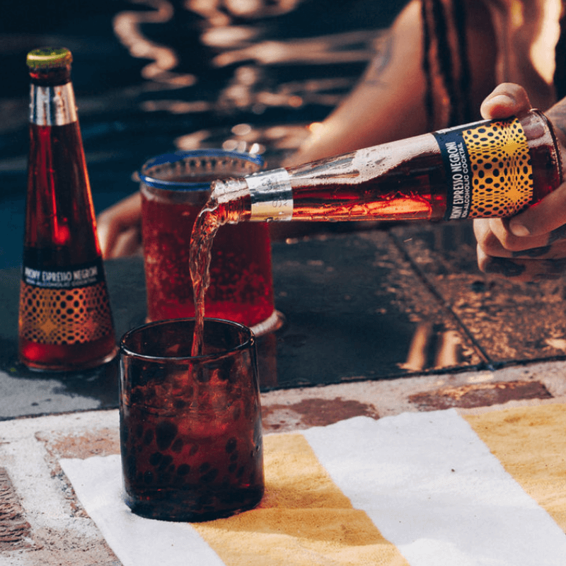 Person pouring a bottle of Phony Espresso Negroni into a glass