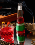 Bottle of Phony Mezcal Negroni with a cocktail on a reflective surface, record player in the background
