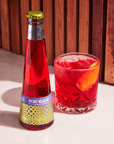 Bottle and glass of Phony Negroni against a wooden background