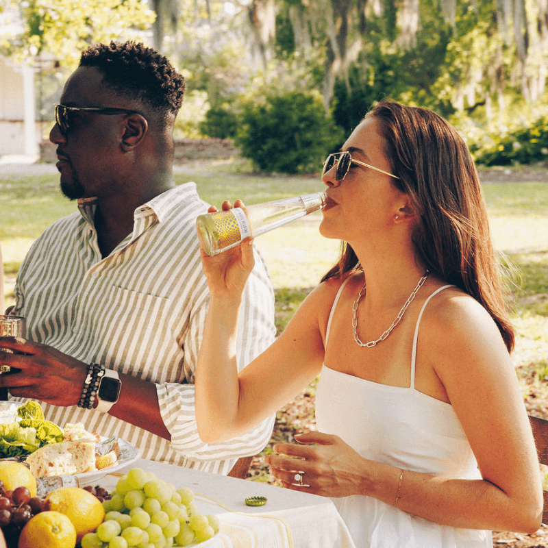 Man and woman enjoying Phony White Negroni outdoors with a table of food