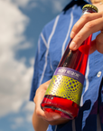 Person holding a bottle of Phony Negroni against a blue sky.