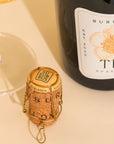 Bottle of Susurrus Tea Sparkling Wine with cork and glass on a light surface