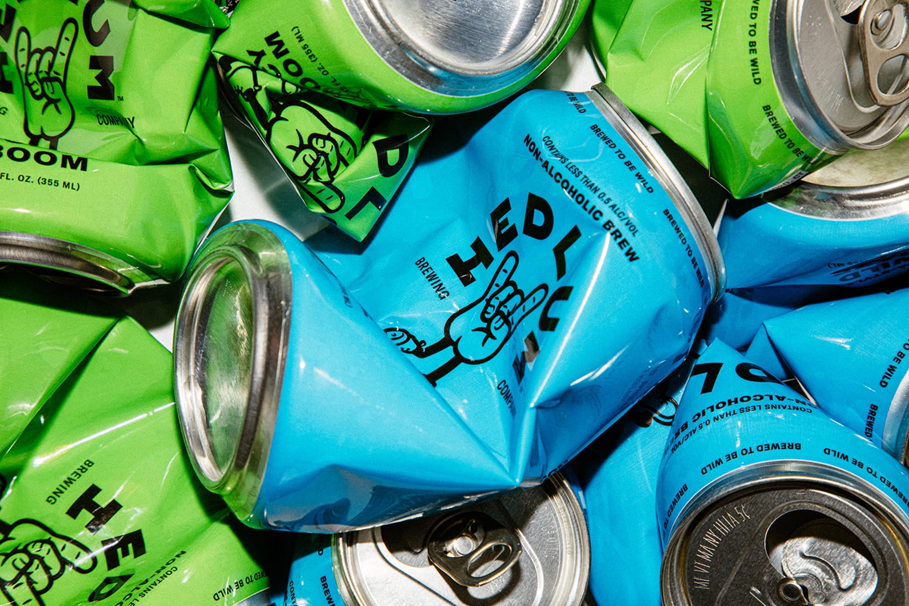 Pile of blue and green cans with 'HEDL' branding on a white background
