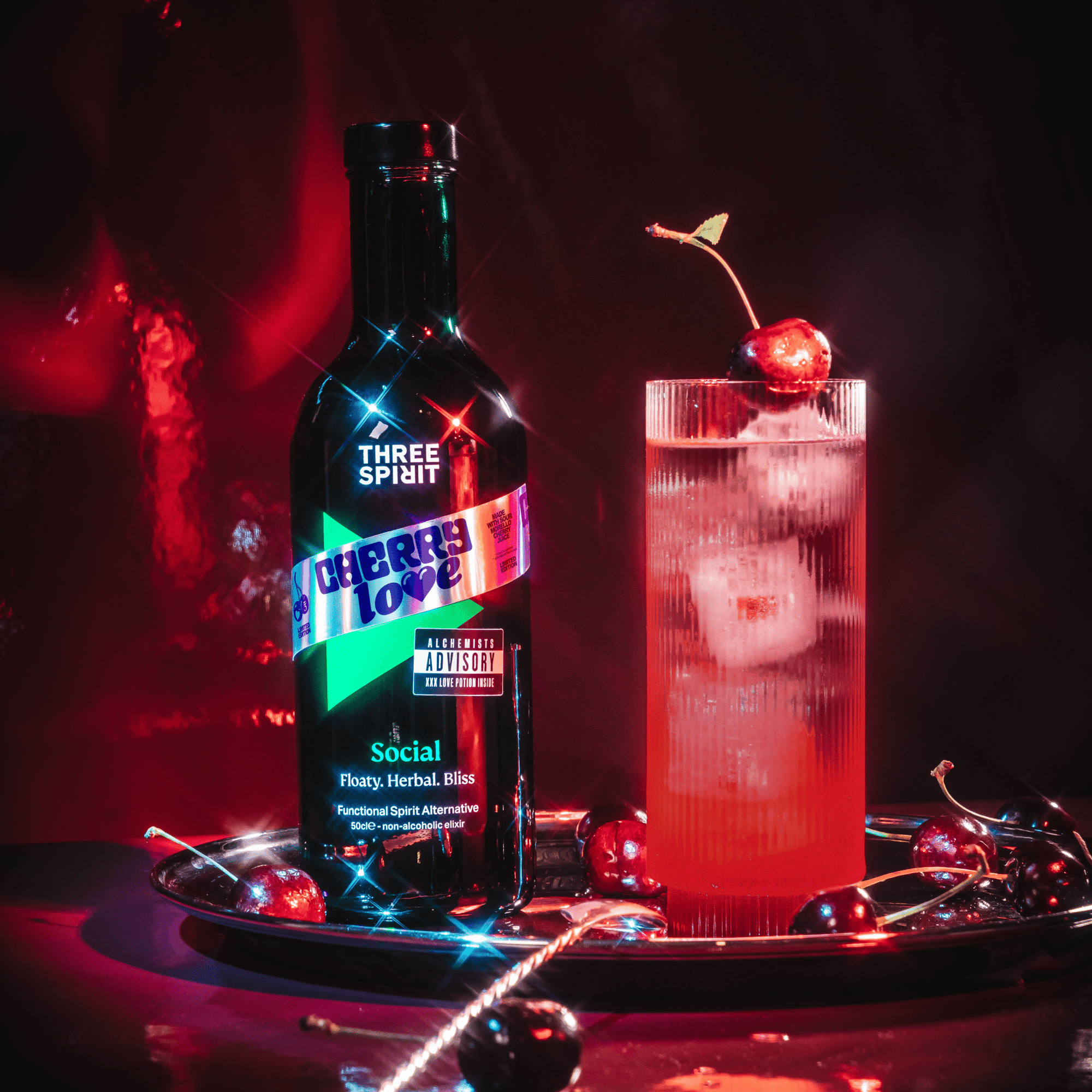 Bottle of &#39;Three Spirit Cherry Love&#39; with a cocktail garnished with a cherry on a dark background