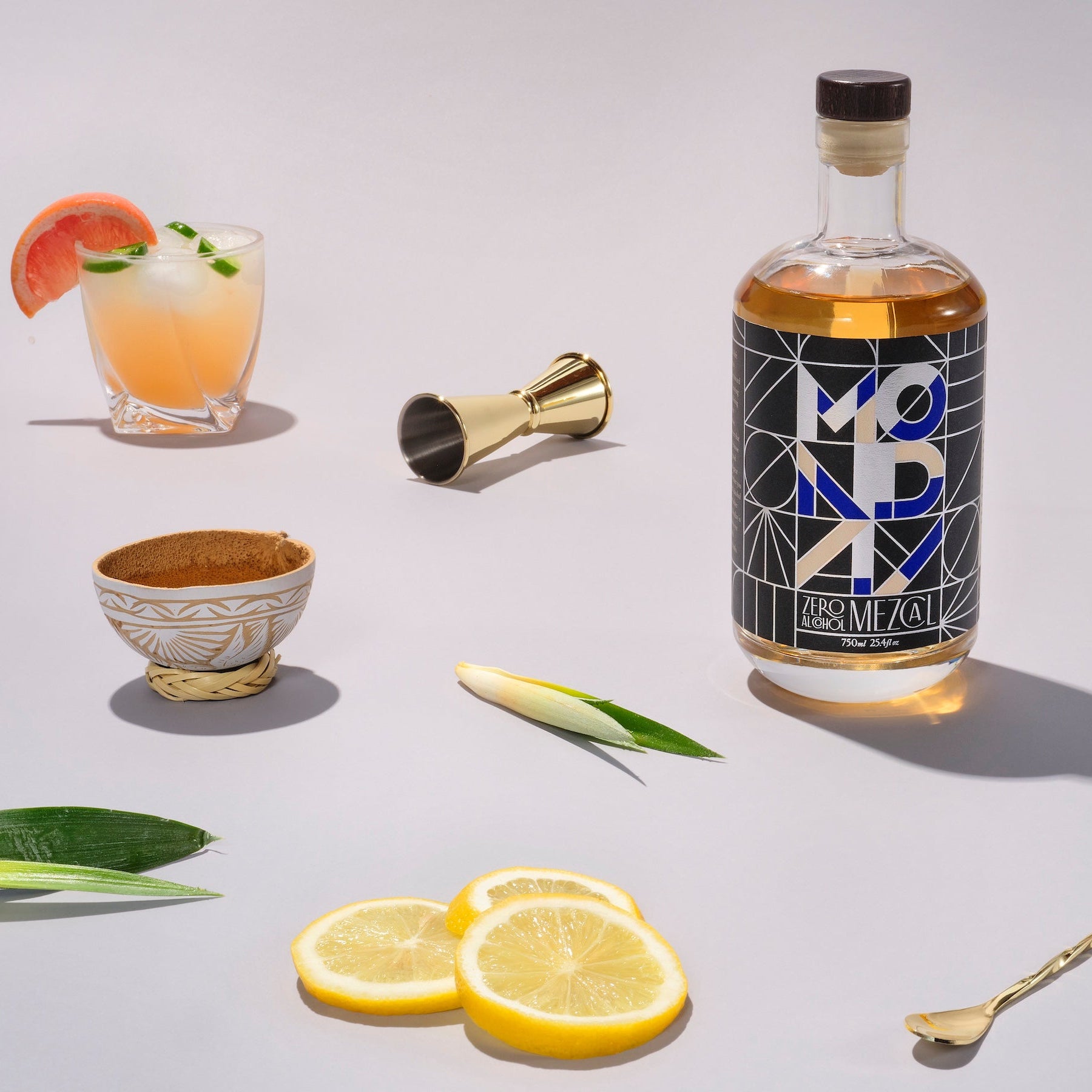Bottle of Absolut Vodka with cocktails and garnishes on a light background